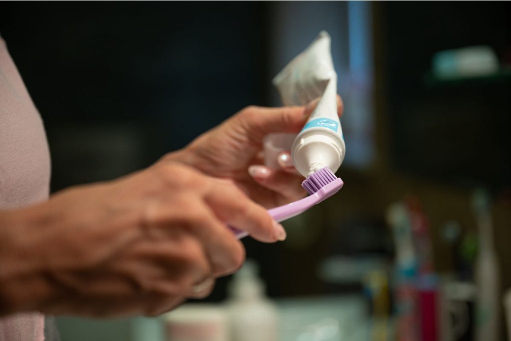 Person putting toothpaste on toothbrush